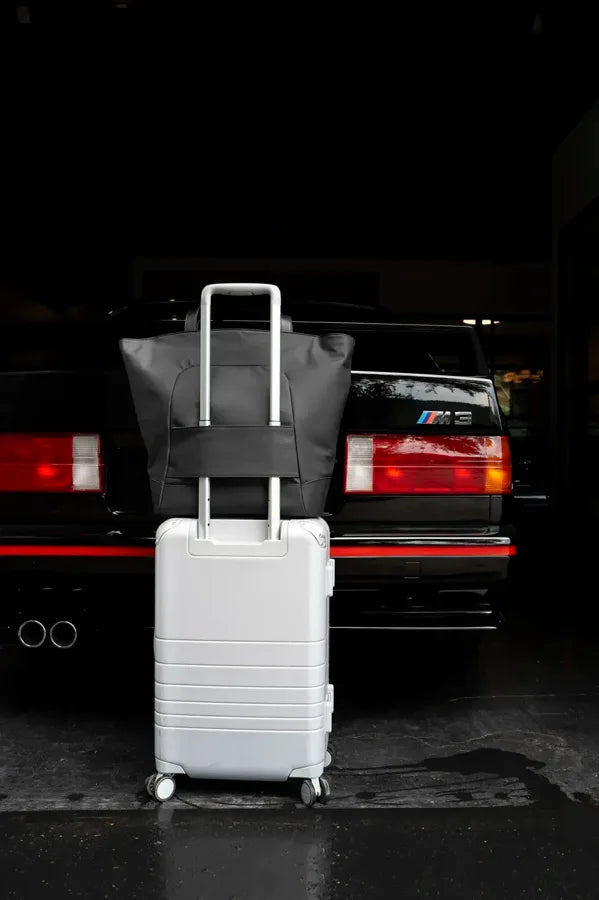 The Asset with rolling luggage beside a car